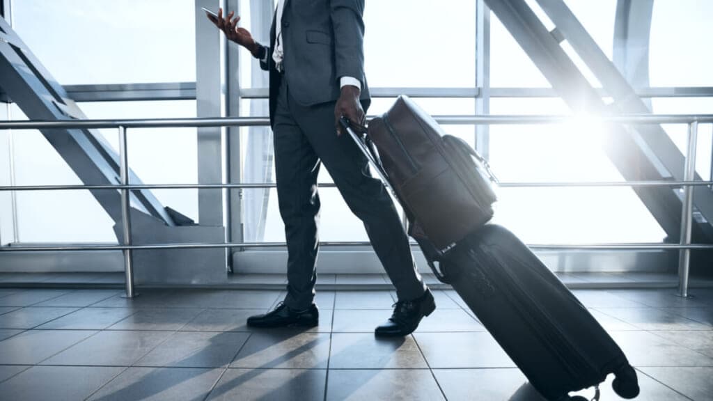 A man pulling luggage and holding a cell phone