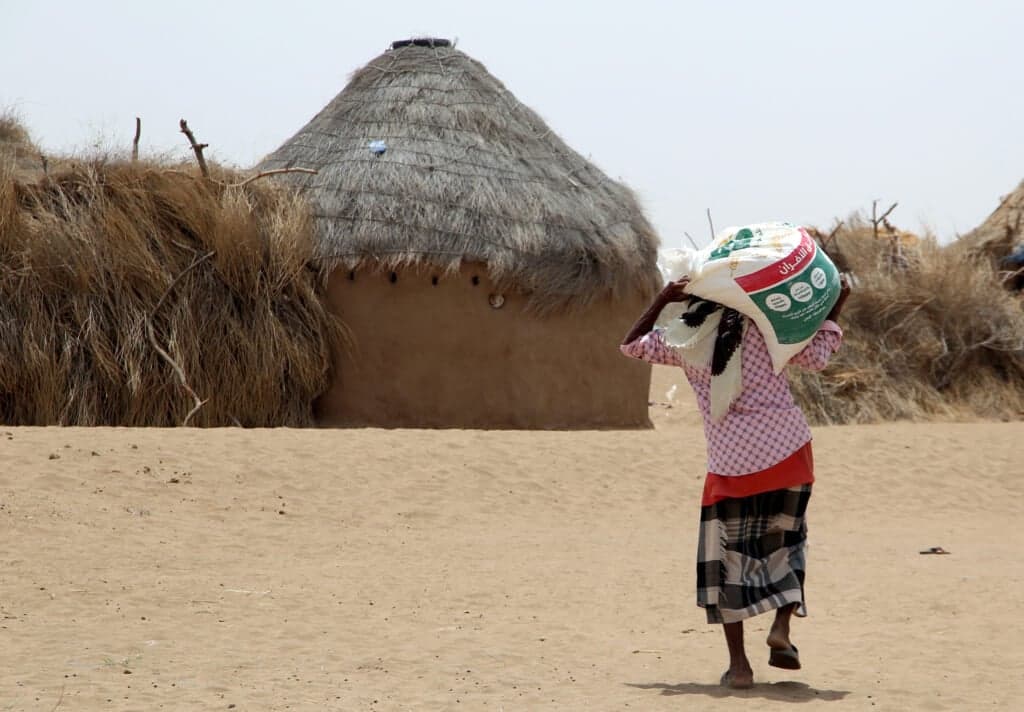 A displaced Yemeni receives food aid and supplies at a camp
