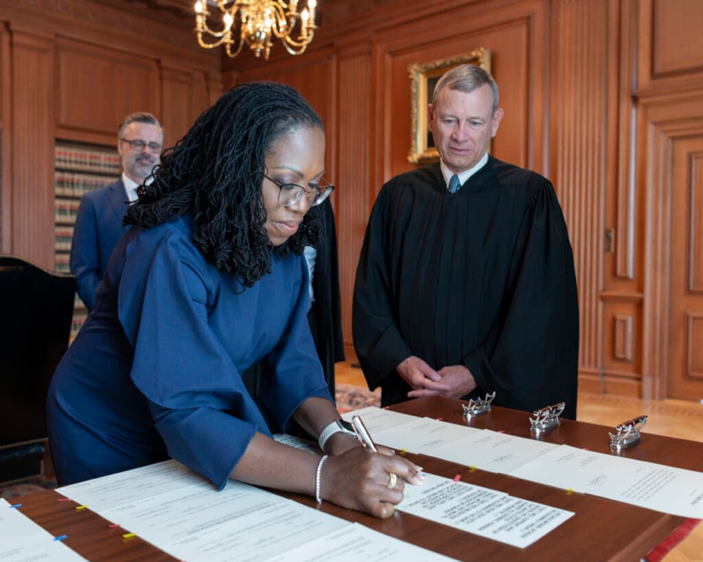 Chief Justice John G. Roberts, Jr. (right) looks on as Justice Ketanji Brown Jackson signs the Oaths of Office