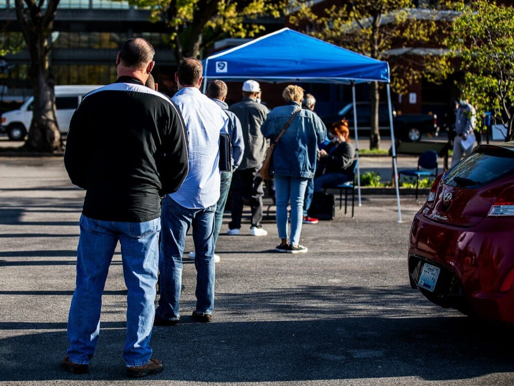 People in line in front of a blue canopy