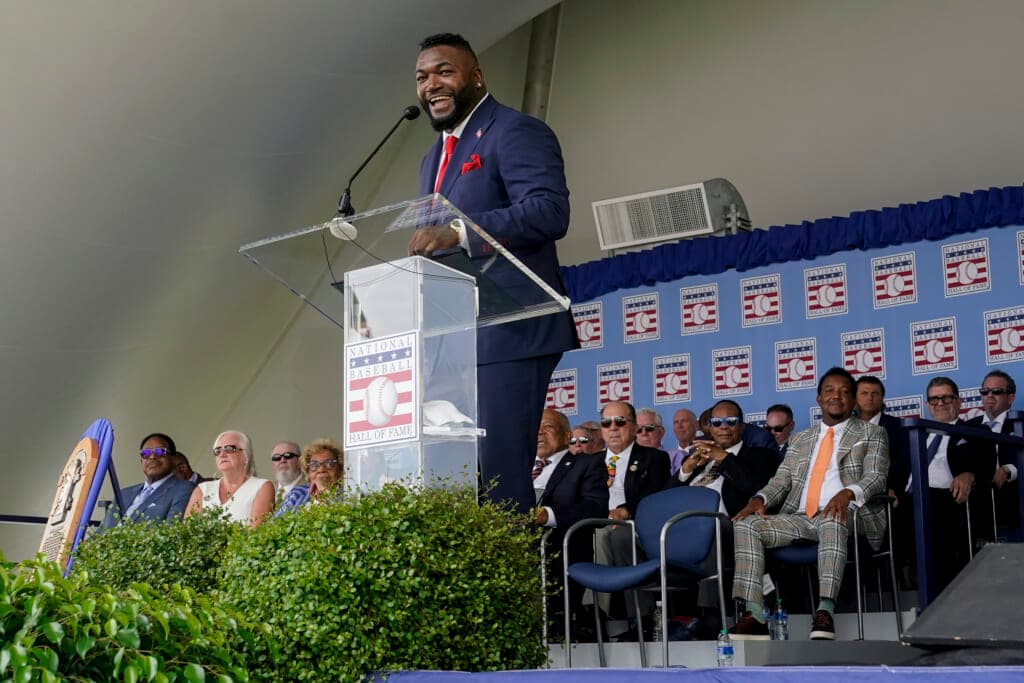 Hall of Famer David Ortiz, formerly of the Boston Red Sox, stands at a clear Lucite podium smiling