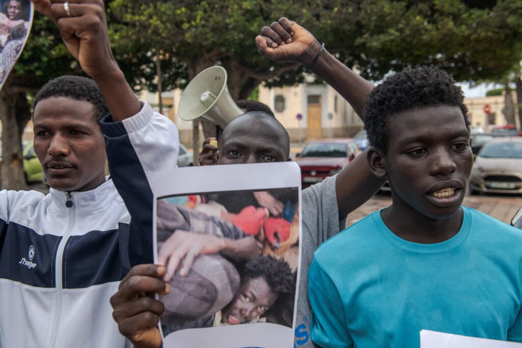 Protester hold images of the violence immigrants suffered