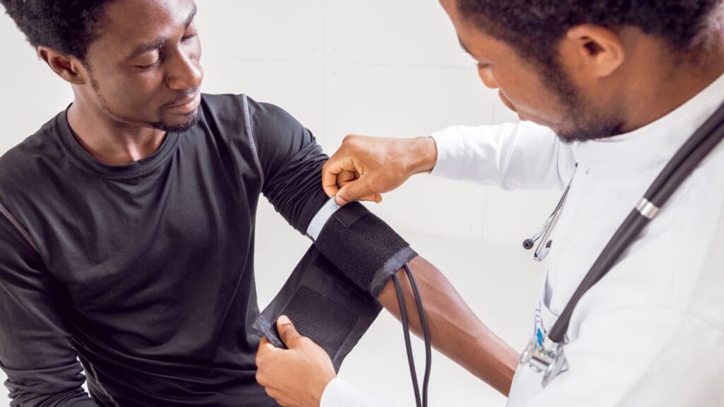A doctor puts a blood pressure cuff on a man's arm