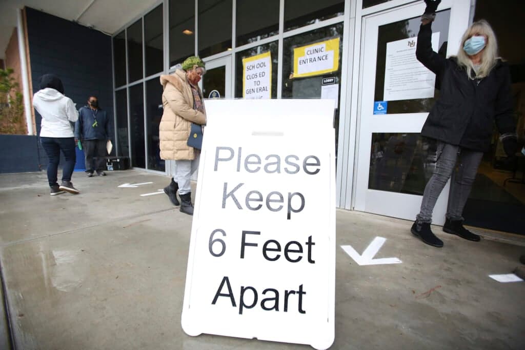 A sign asks those getting vaccinated to keep 6 feet apart