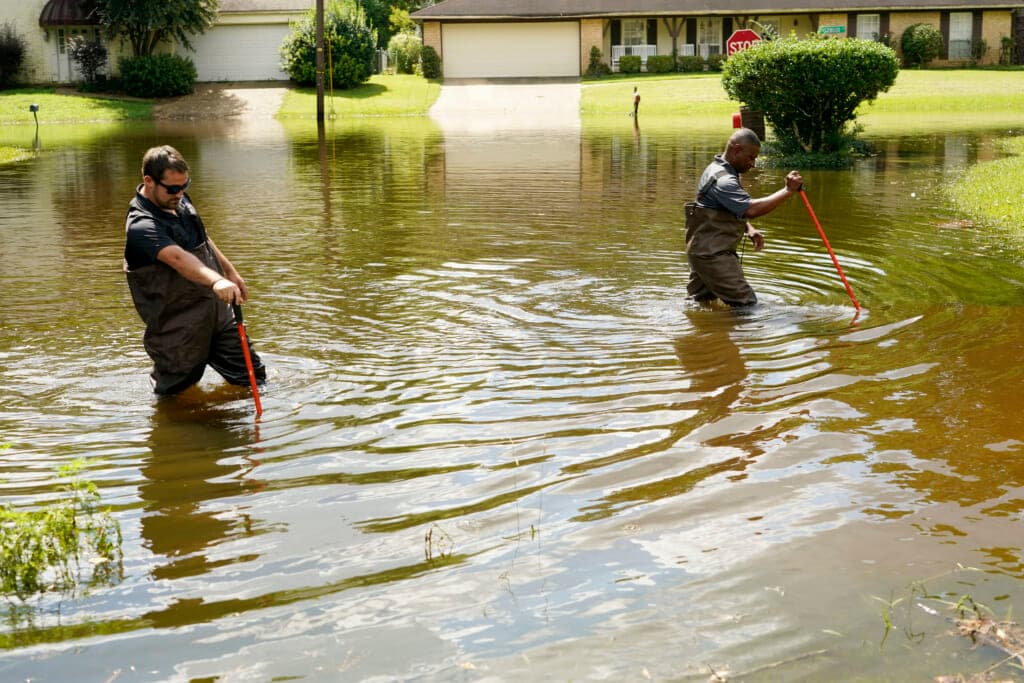 Hinds County Emergency Management Operations personnel Luke Chennault and Tracy Funches wade through flood waters