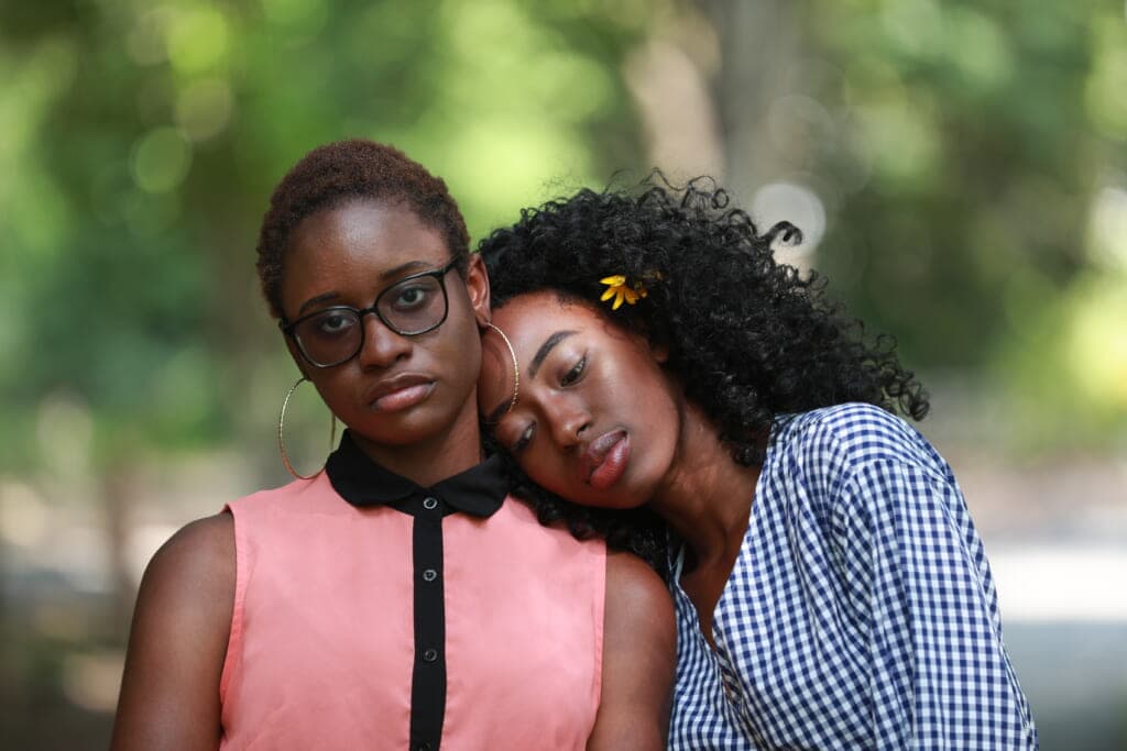 A woman lays her head on another woman's shoulder