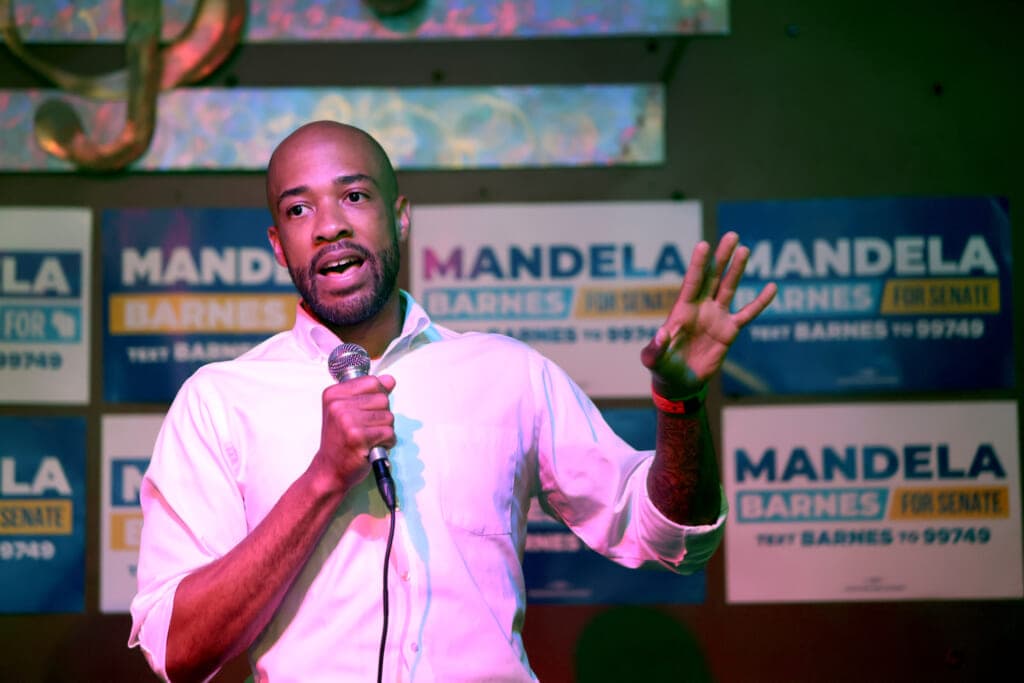 Wisconsin Lieutenant Governor Mandela Barnes holds a microphone as he gesture, wearing a white shirt