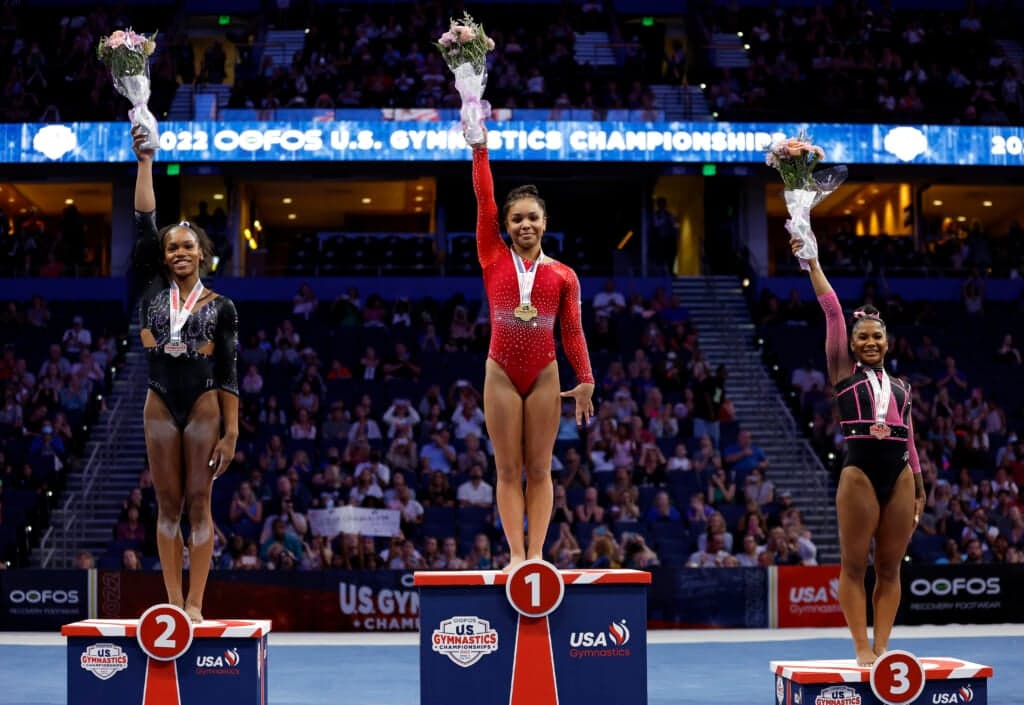 Shilese Jones, Konnor McClain and Jordan Chiles raise bouquets as they stand on winners' blocks
