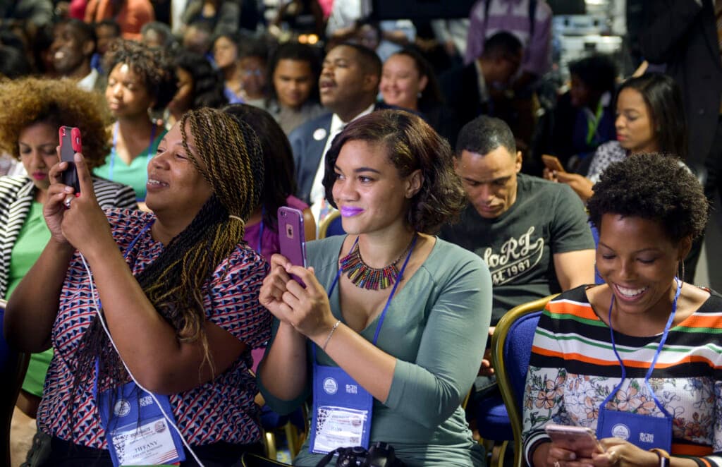 Seated audience members hold up cell phones
