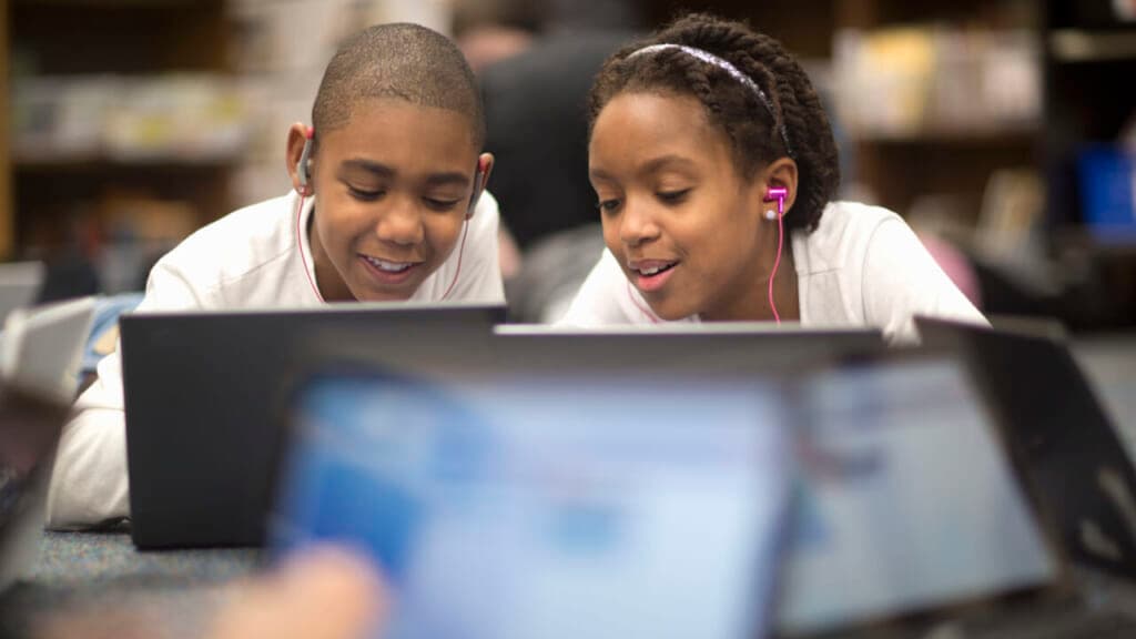 Two children use laptops