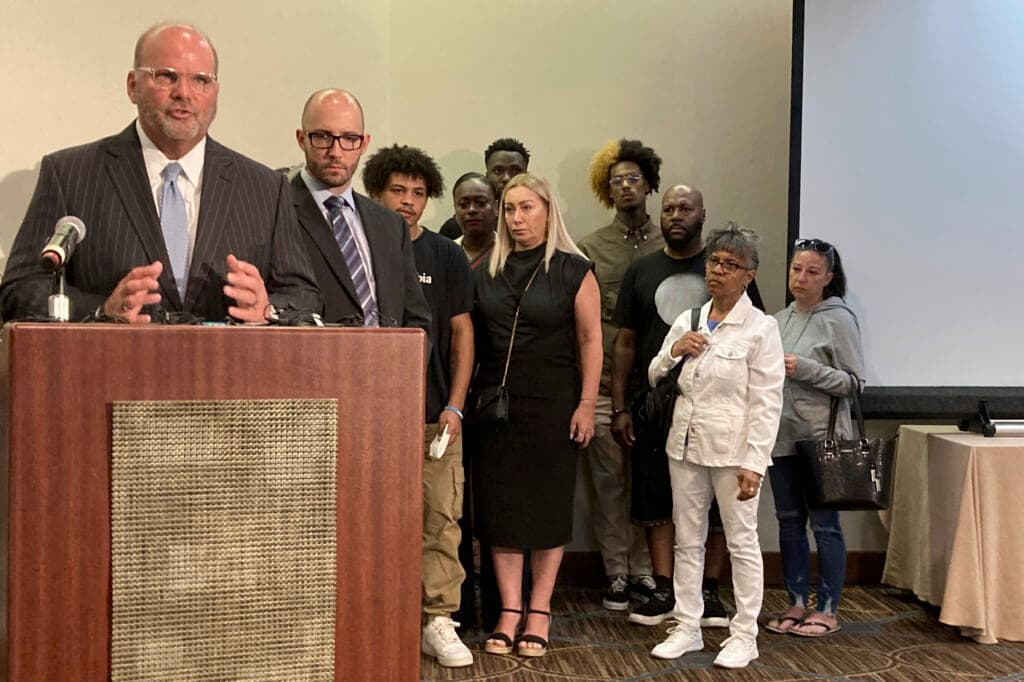 Attorney Rex Elliott addresses reporters with the extended family of Donovan Lewis behind him