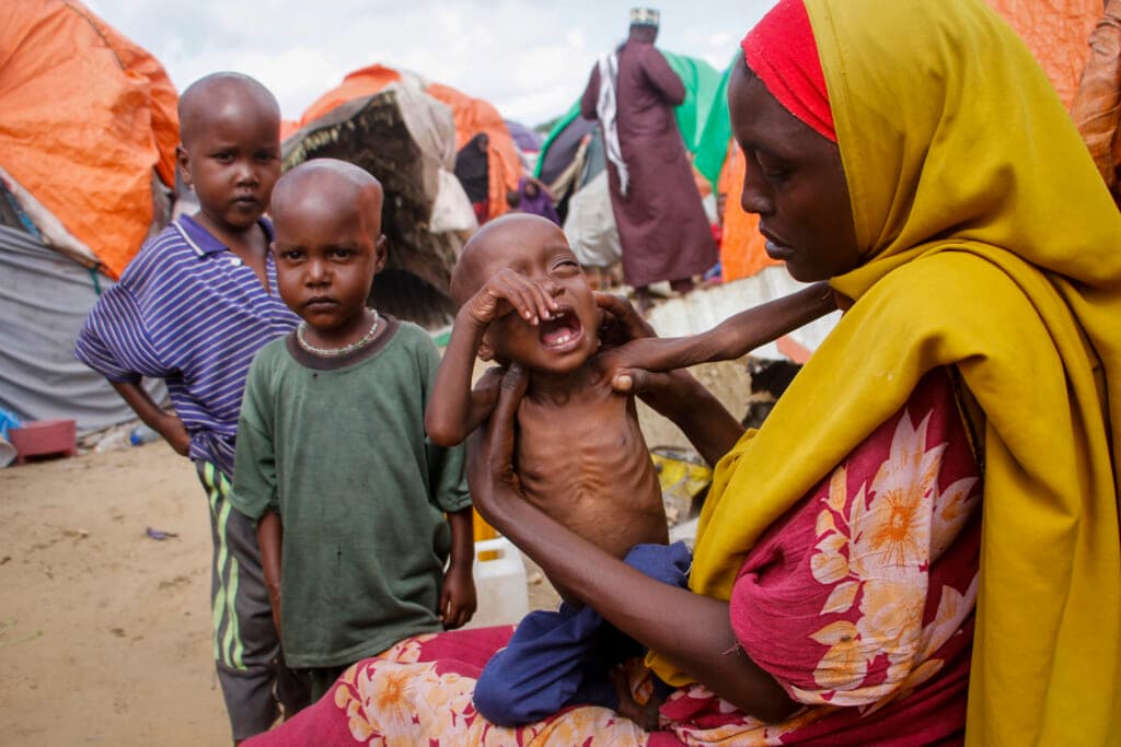 Maryan Madey holds her crying, malnourished daughter Deka Ali