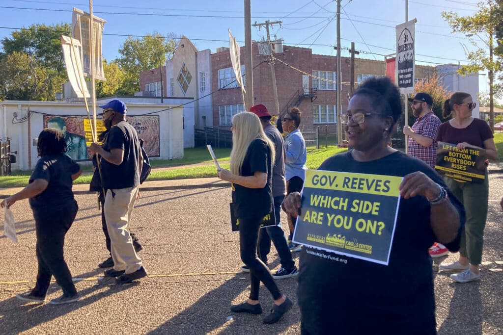 A protestor holds a sign aimed at Mississippi Gov. Tate Reeves during a protest