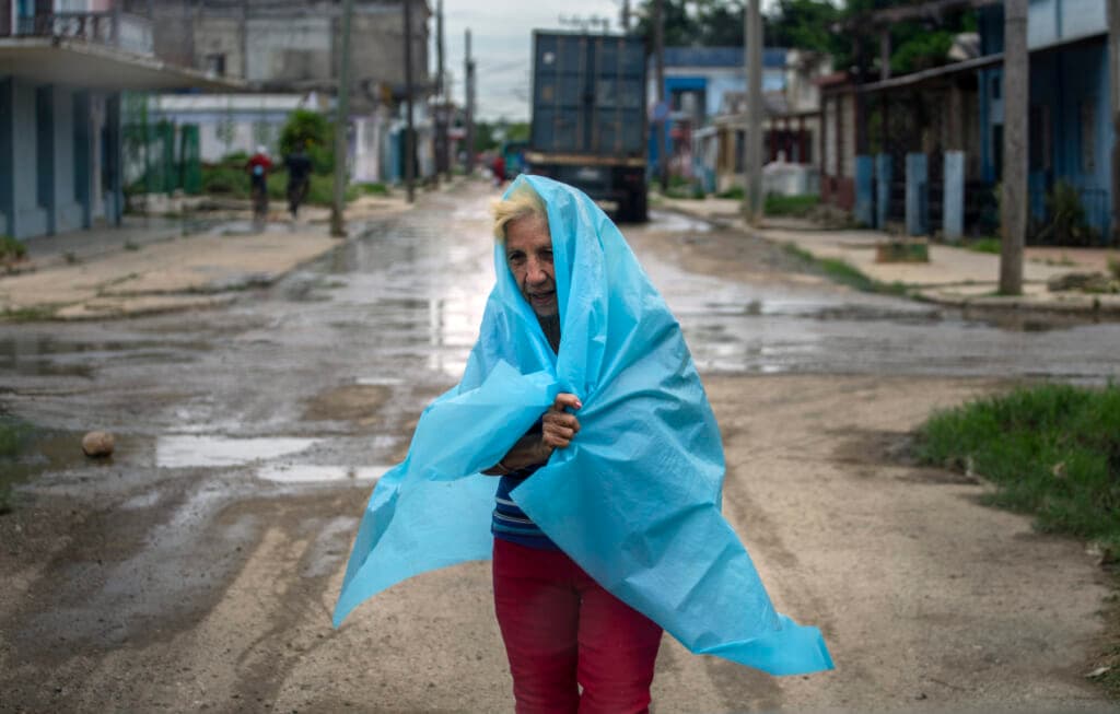 A resident uses plastic as protection from the rain in Batabano, Cuba