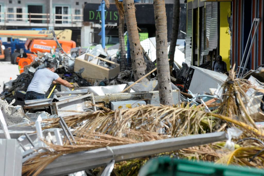A man hauls debris away from a pizza restaurant that was badly damaged by Hurricane Ian