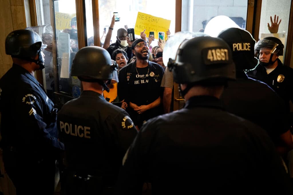 Police officers in riot gear in front of a group of protesters