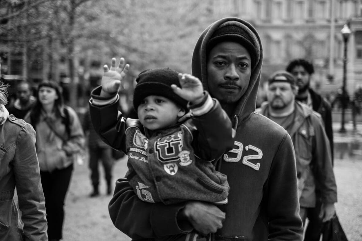 A man in a hoodie holds a baby