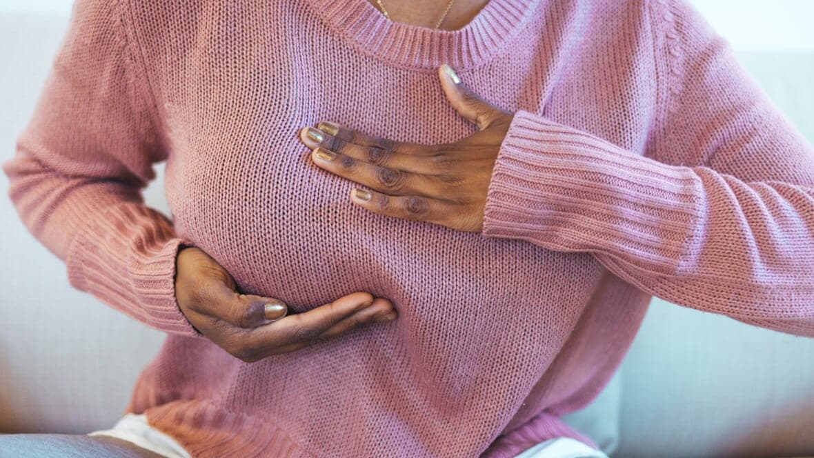 A woman's hands indicating her right breast