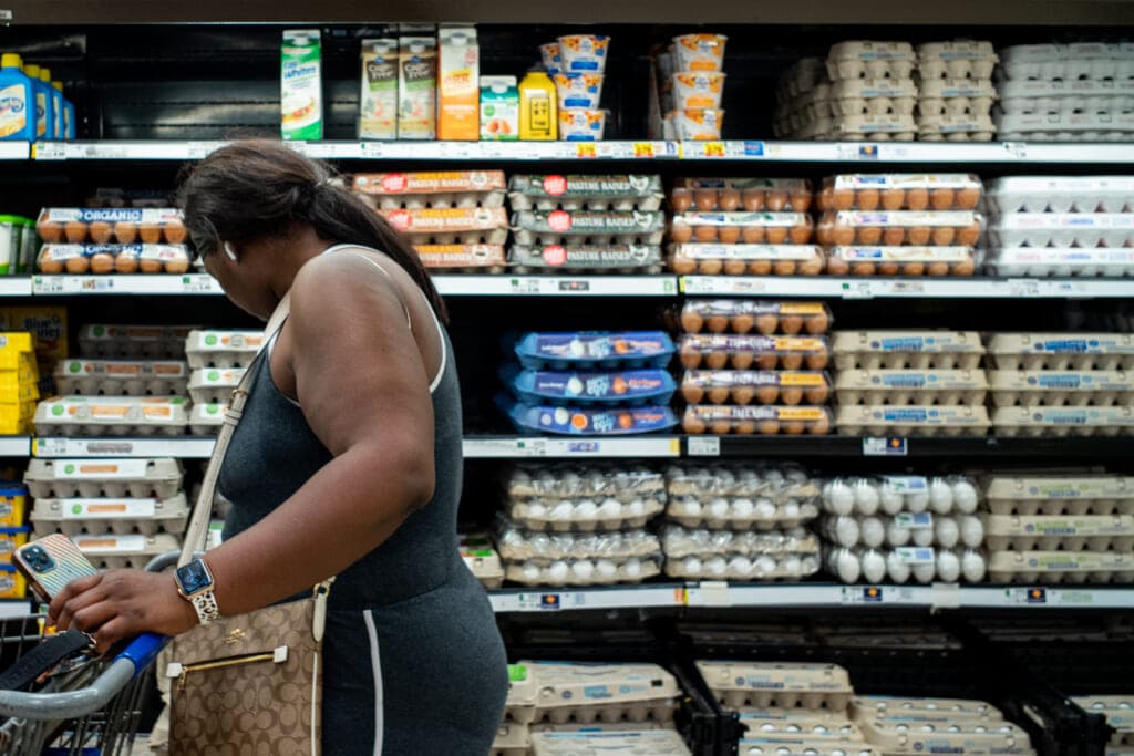 A woman buying eggs at a grocery store