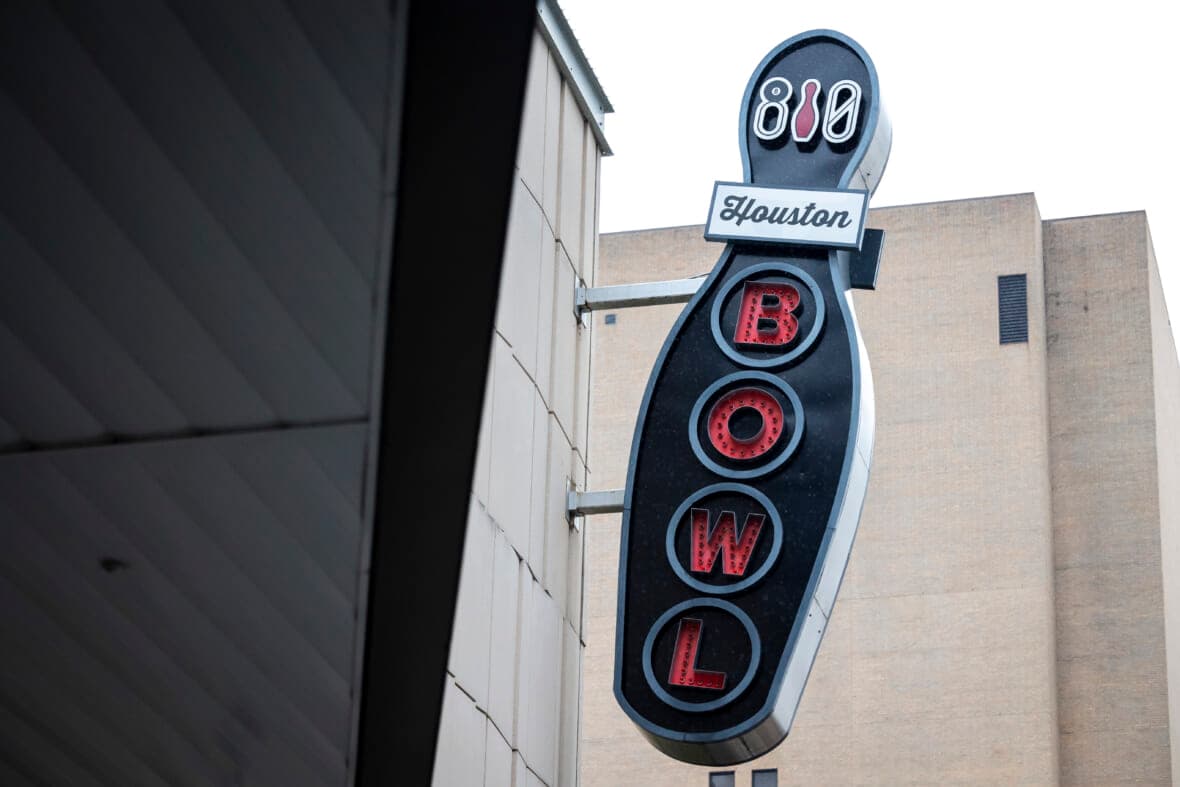 A sign for 810 Billiards & Bowling hangs from the side of building