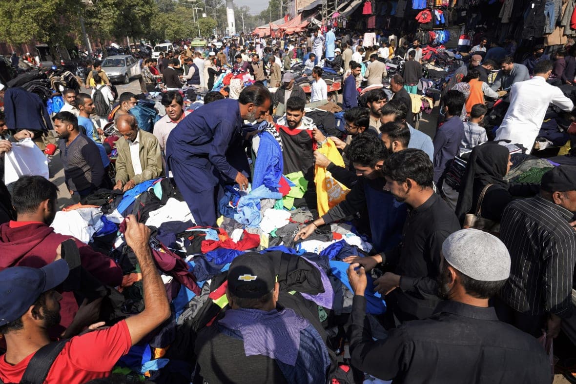 People buy clothing in a crowded marketplace
