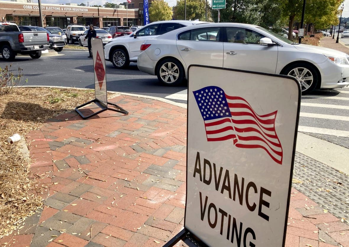 A sign for advance voting on a brick sidewalk