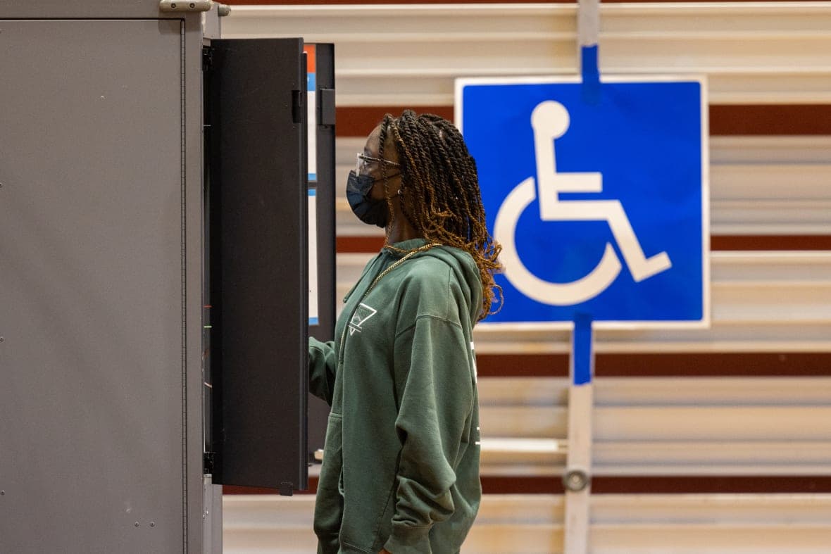 A woman stands at a voting booth