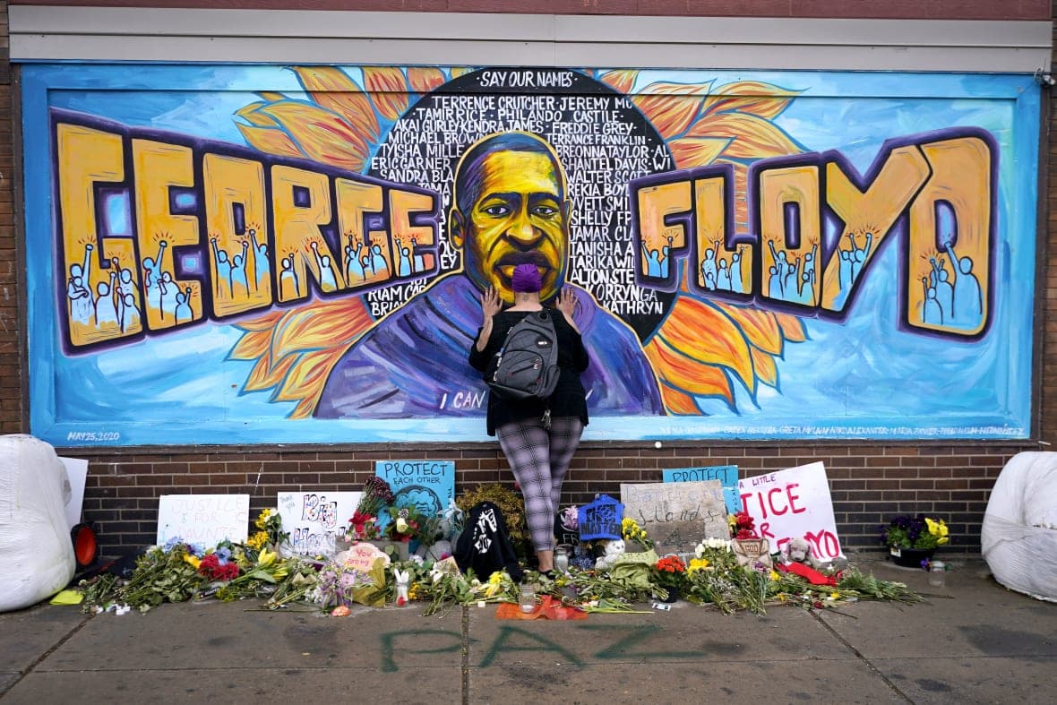 Damarra Atkins pays respect to George Floyd at a mural at George Floyd Square