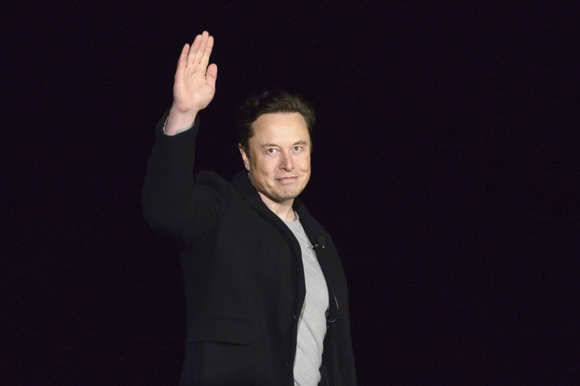 SpaceX CEO Elon Musk waves, wearing a black coat and white shirt