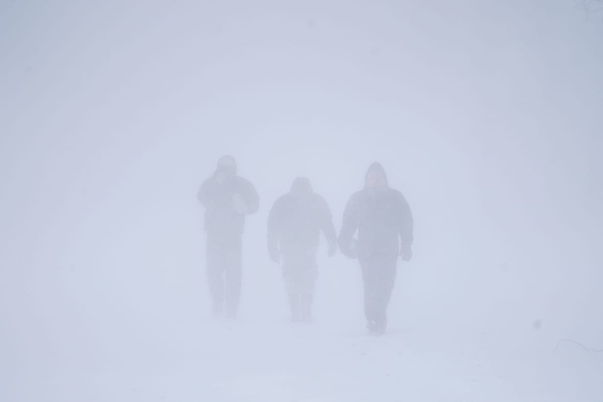 Three men walk down Richmond Avenue in whiteout conditions