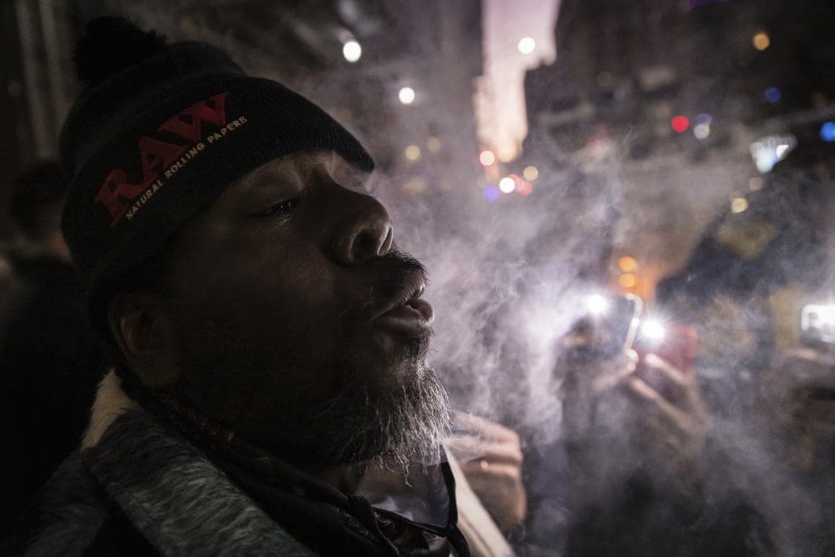 A person exhales while smoking marijuana outside the Housing Works Cannabis Co.