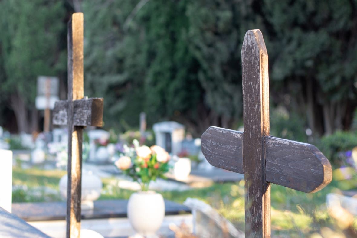 Multiple old brown wooden ruined crosses marking unknown graves in a graveyard