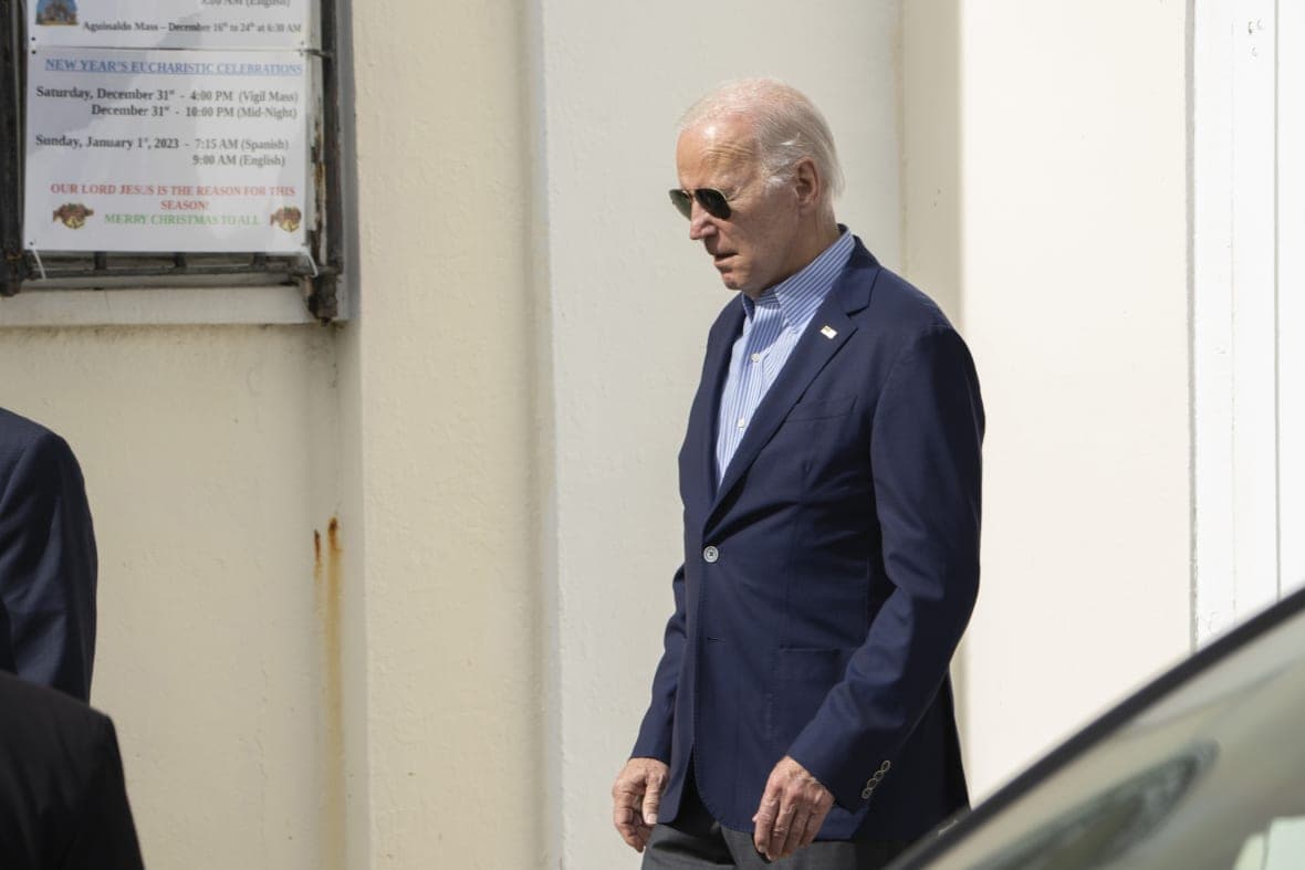 President Joe Biden walking, wearing a blue jacket and blue-striped shirt