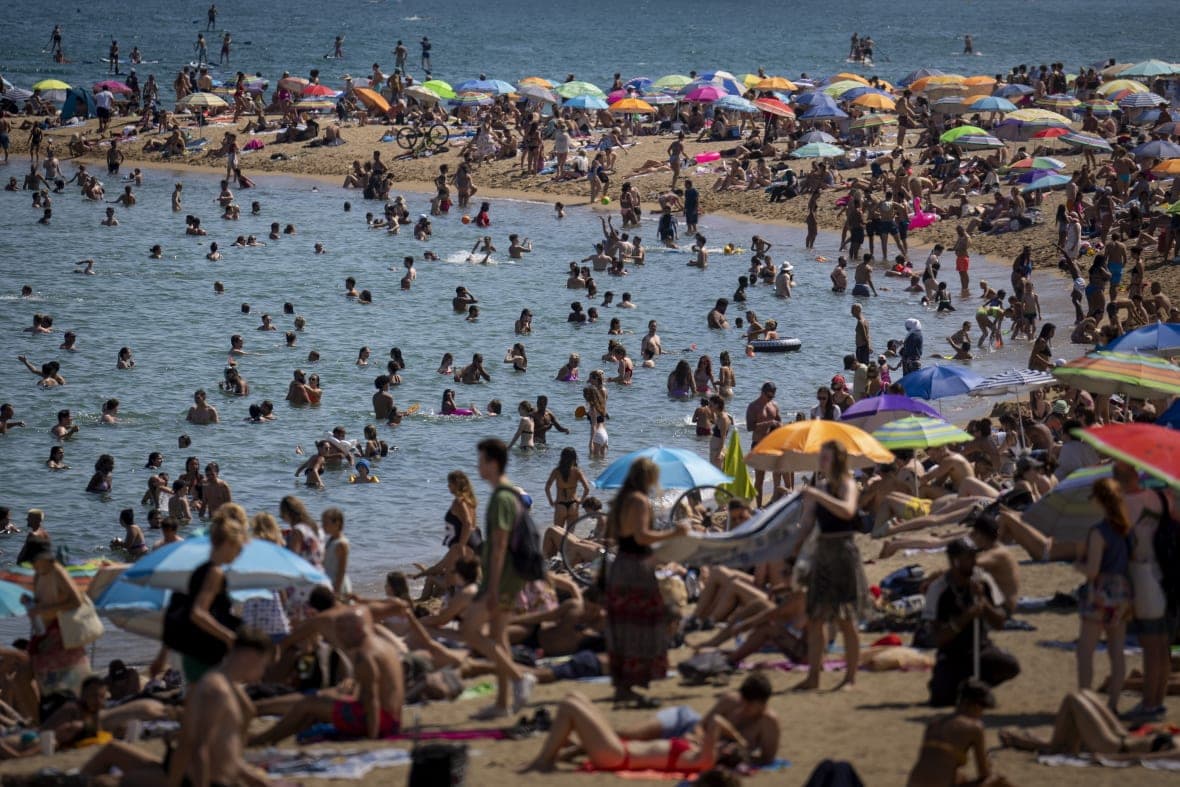 People cool off in the water on a hot and sunny day at the beach in Barcelona, Spain