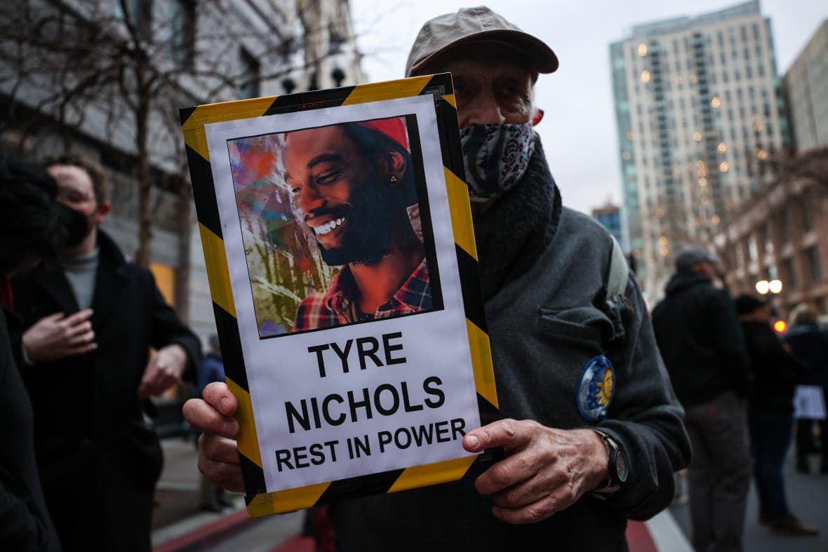A man holds a sign reading "Tyre Nichols, Rest in power"
