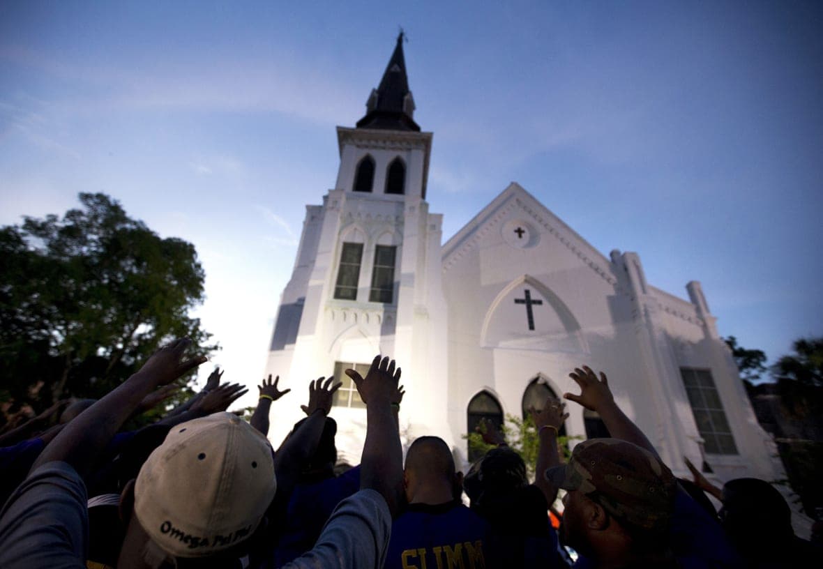 The men of Omega Psi Phi Fraternity Inc. lead a crowd of people in prayer outside the Emanuel AME Church