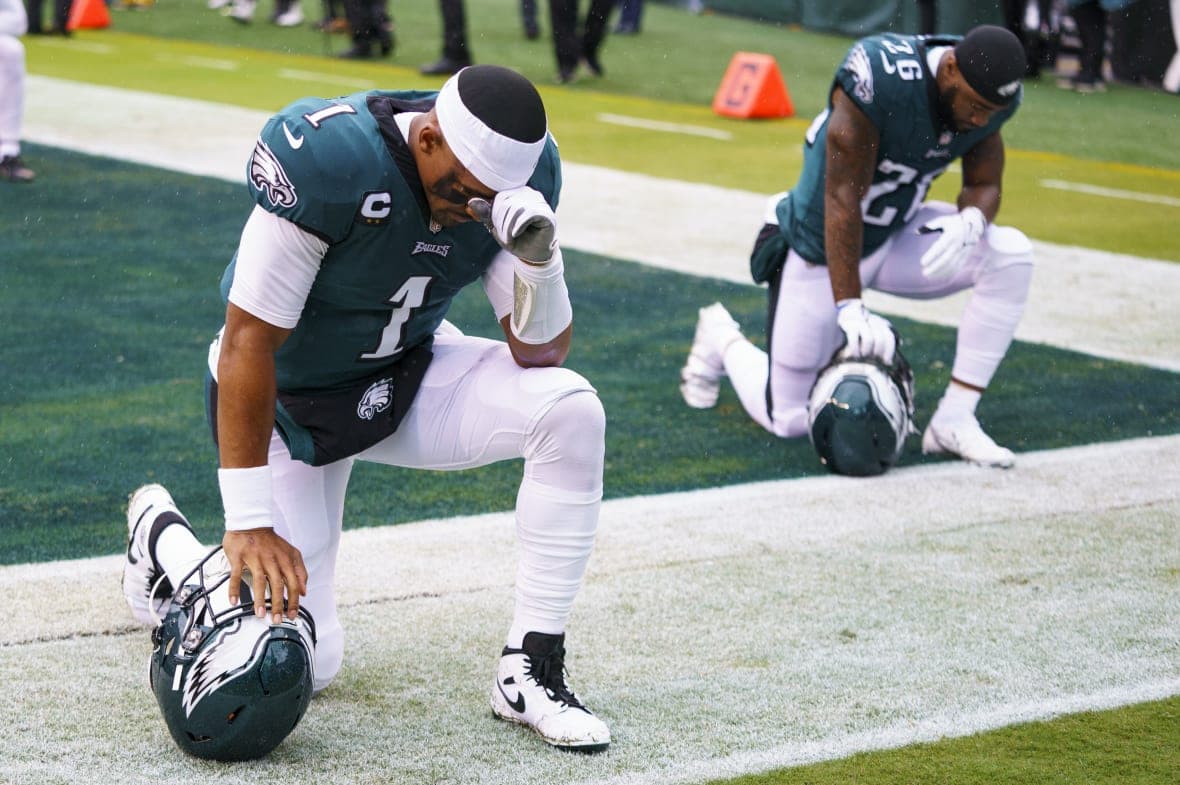 Philadelphia Eagles quarterbacks Jalen Hurts kneels with running back Miles Sanders
