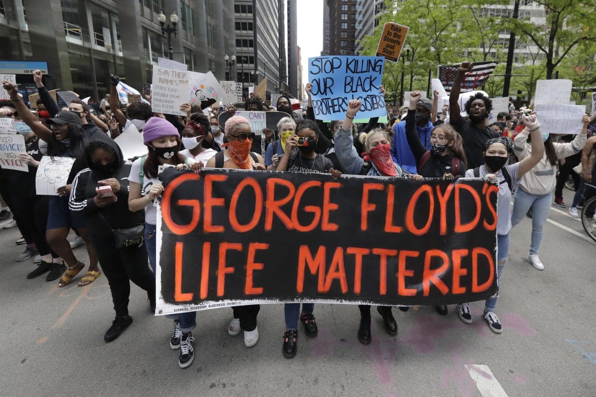 Protesters hold signs as they march during a protest over the death of George Floyd
