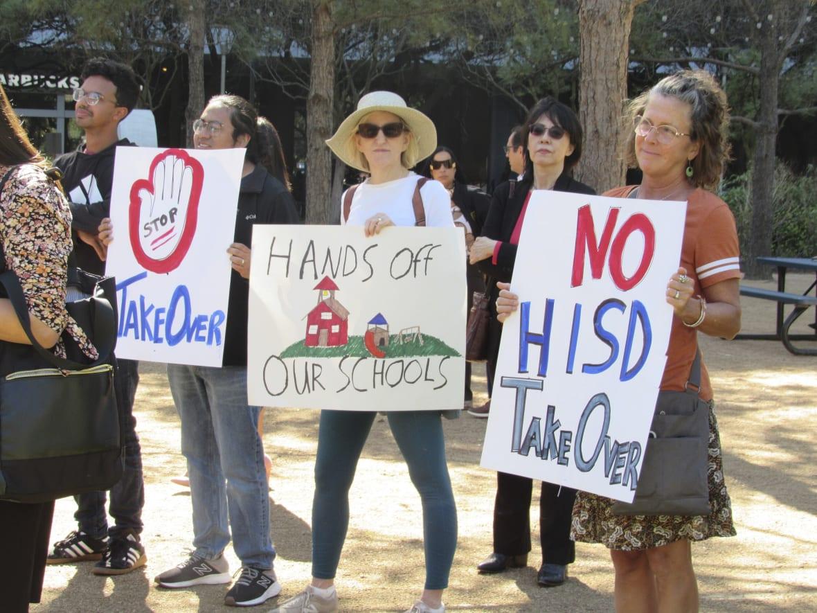 Protesters hold up signs at a news conference