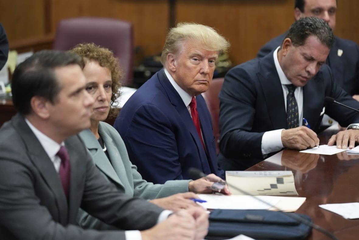 Former President Donald Trump sits at the defense table with his defense team