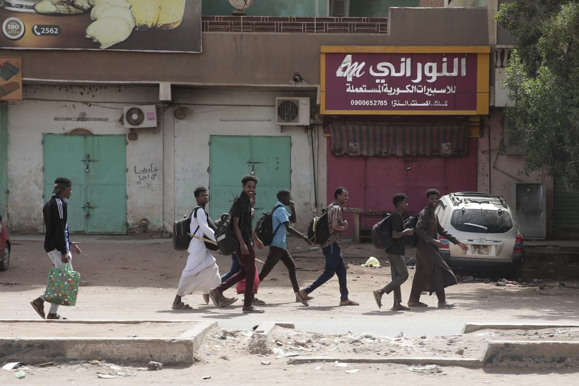 People walk past shuttered shops in Khartoum, Sudan