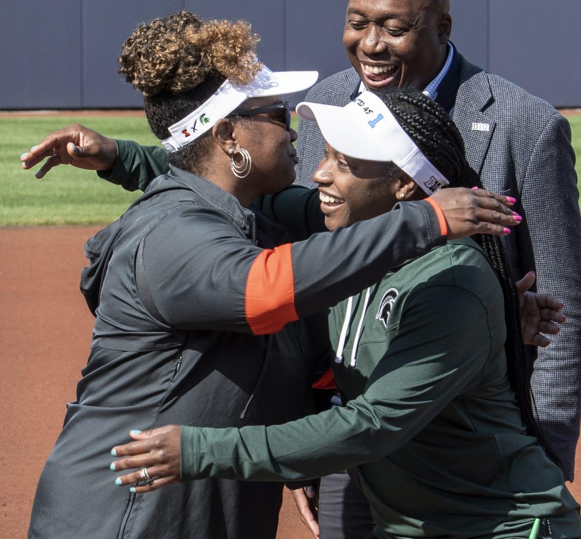 Illinois coach Tyra Perry and Michigan State coach Sharonda McDonald-Kelley hug in front of Derryl Myles