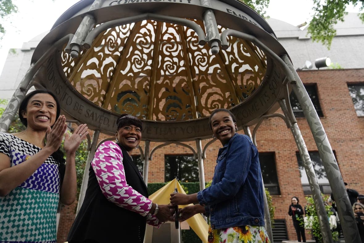 Artist Saya Woolfalk, the Rev. Bernice King and Yolanda Renee King stand underneath the Coretta Scott King monument