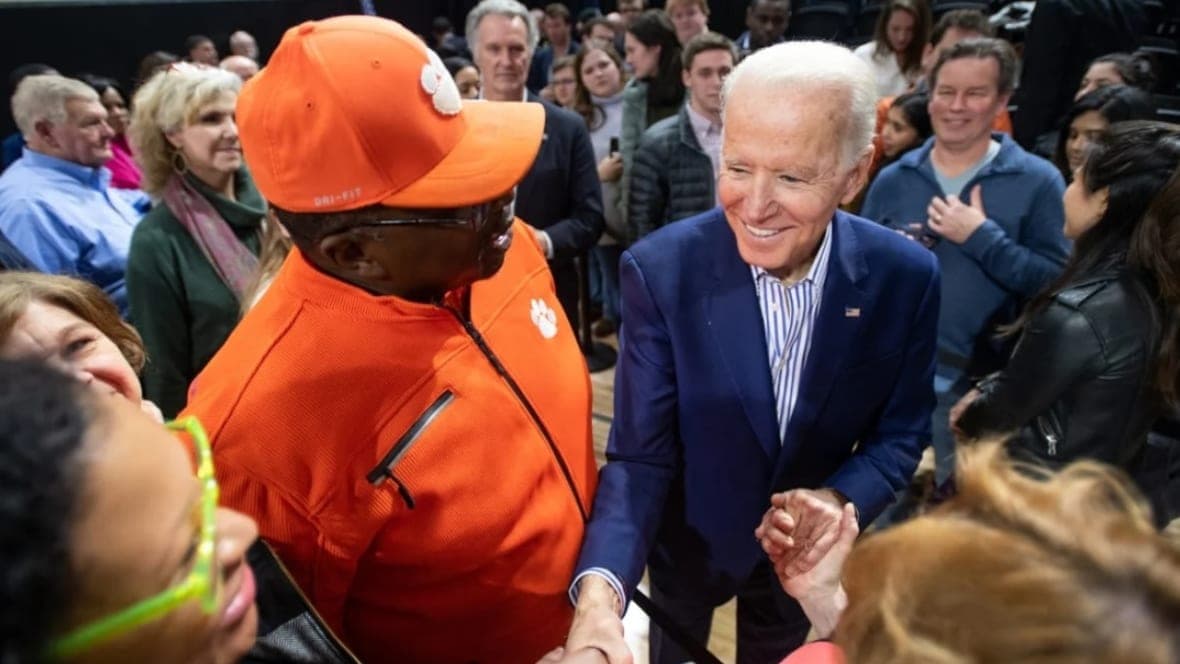 President Joe Biden, wearing a blue suit and a blue-striped shirt, shakes hands with supporters