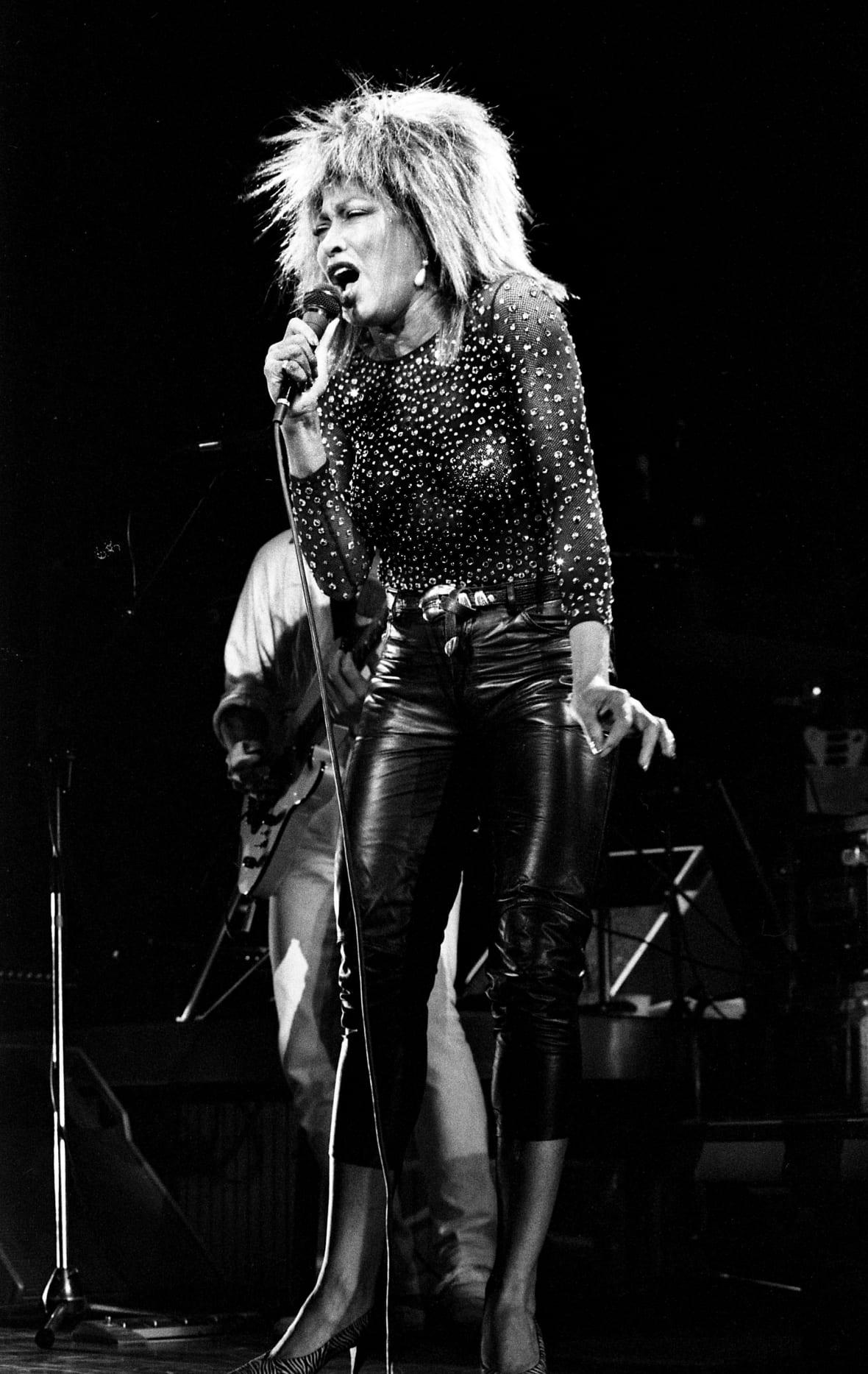 Black-and-white photo of singer Tina Turner holding a microphone on stage