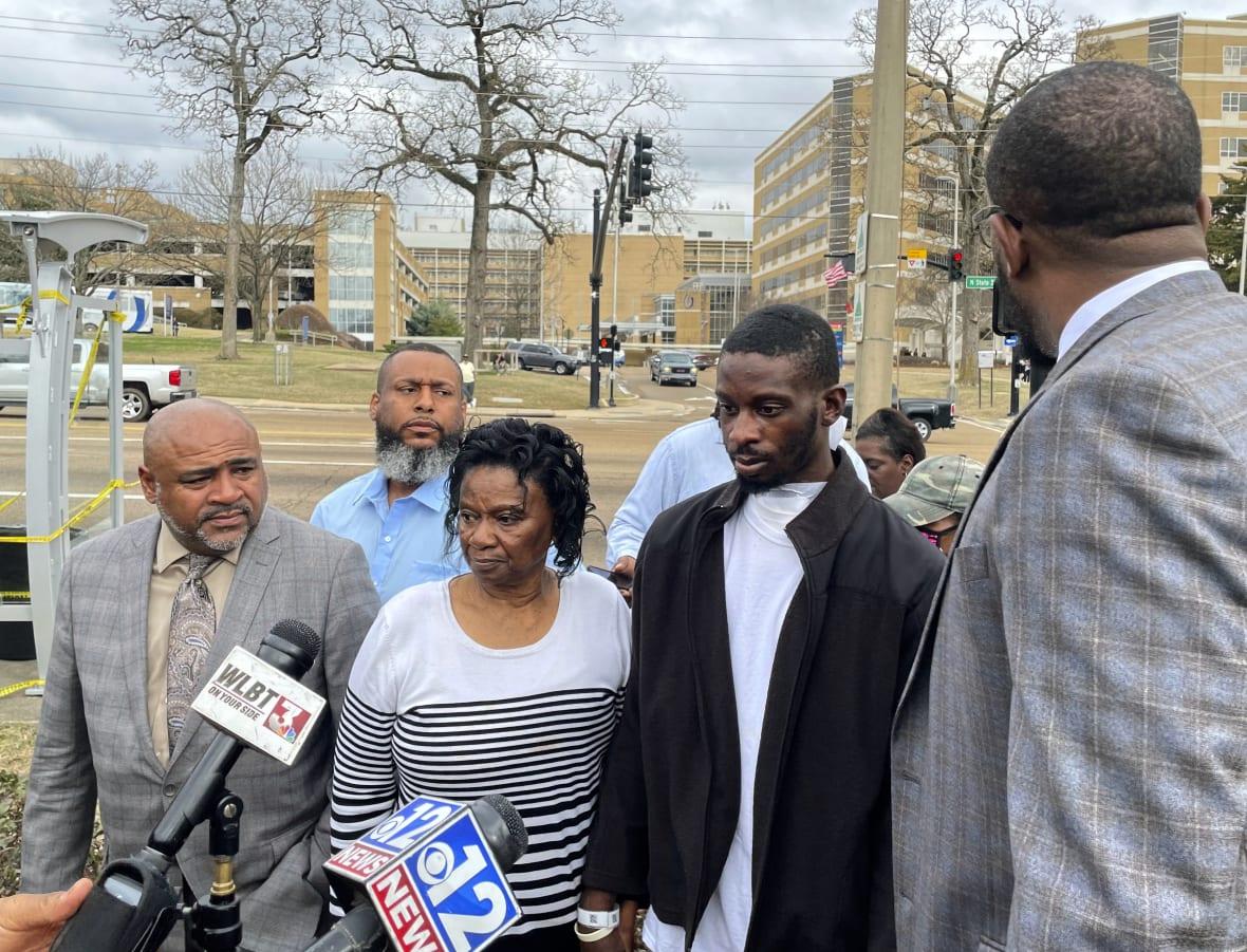 Michael Jenkins, second from right, his mother, Mary Jenkins, center, and their attorneys