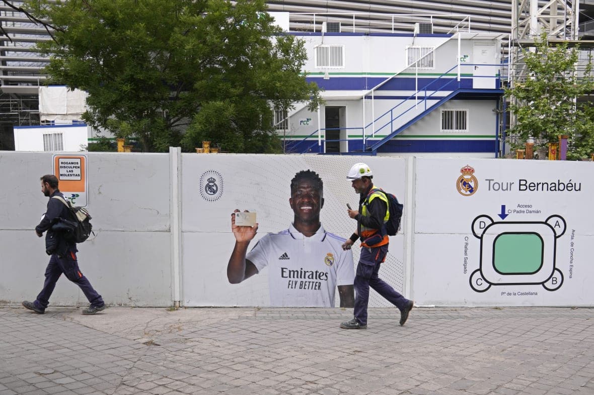Workers pass a poster of Real Madrid’s Vinicius Junior