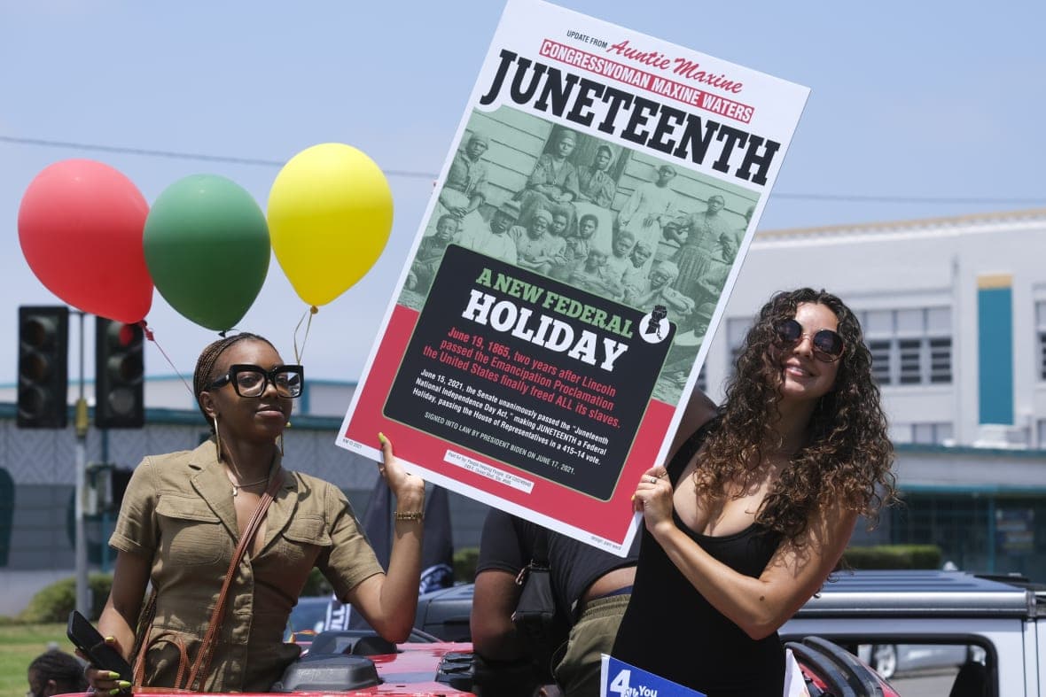 People hold a sign marking Juneteenth