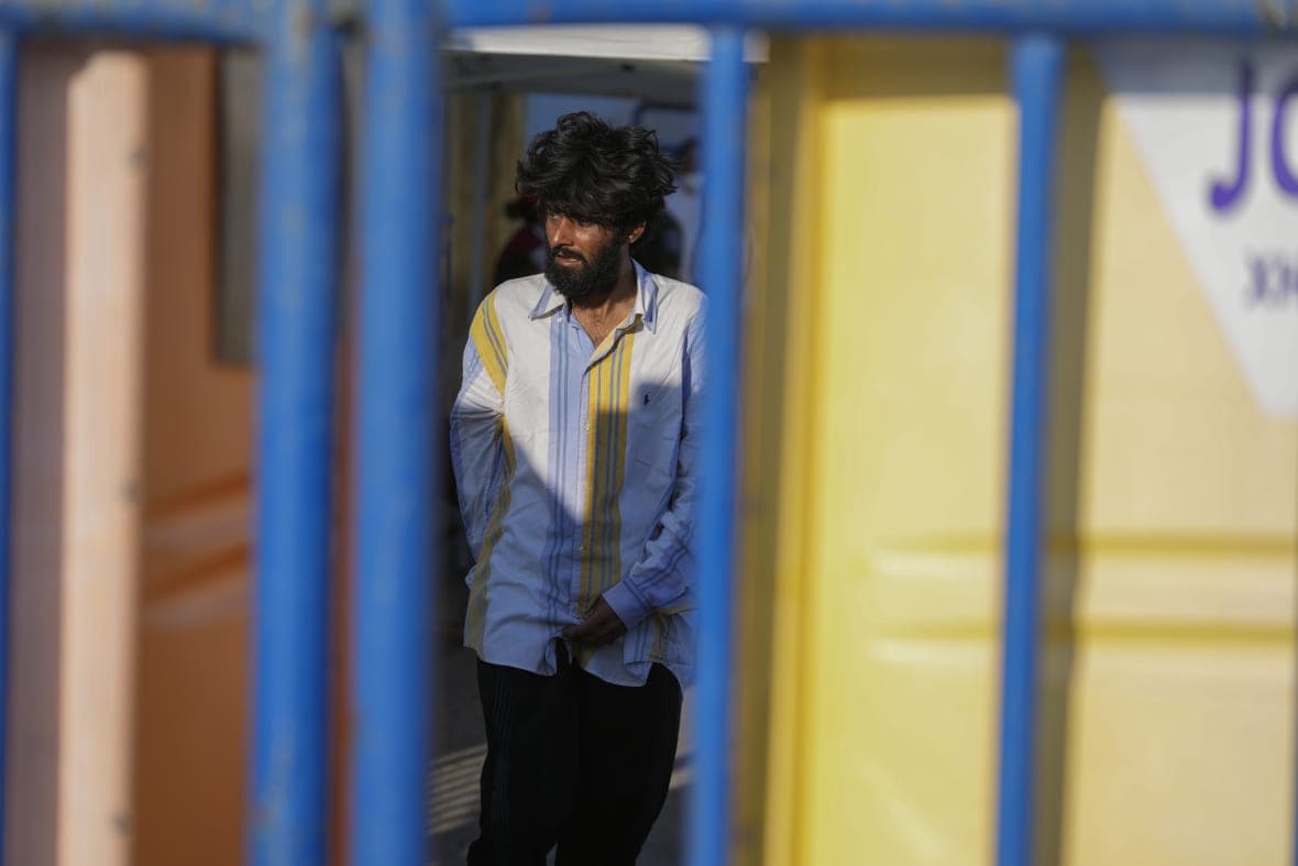 A survivor of a shipwreck walks outside a warehouse