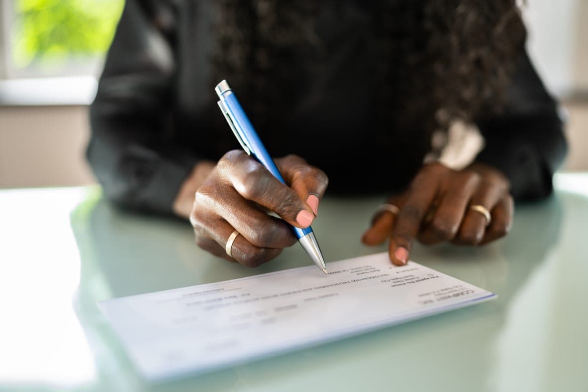 A person at a desk signs a check